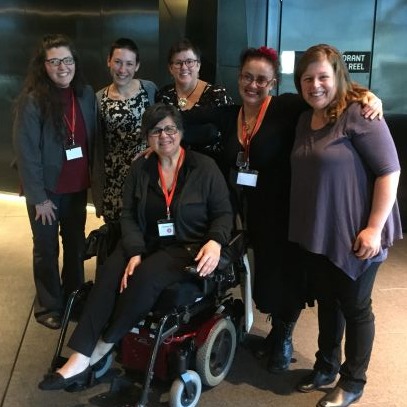 Group of five people standing, one in a wheelchair