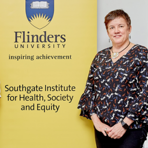 Portrait of Anne standing next to Fllinders University banner