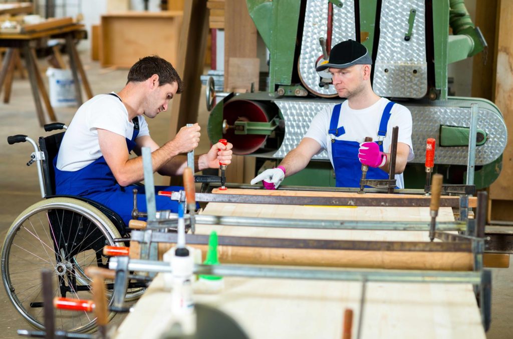 two men in blue overalls using machinery at a workbench